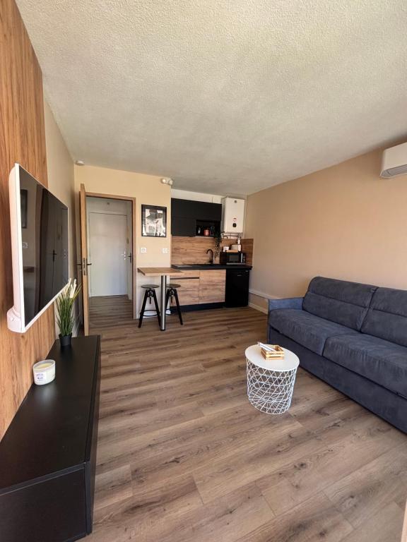 un salon avec un canapé bleu et une cuisine dans l'établissement Studio Le saint Clair centre port, au Cap d'Agde