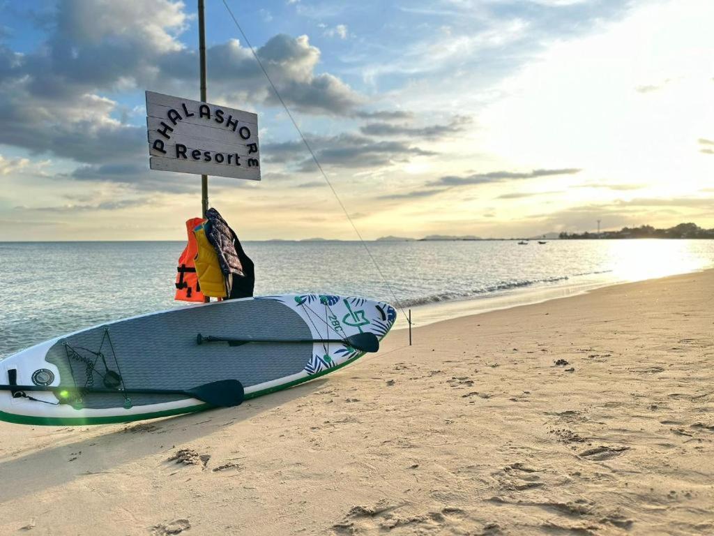 a surfboard on the beach with a sign on it at Phala Shore Resort in Ban Phala