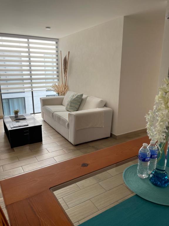 a living room with a white couch and a table at Departamento cerca Palacio Deportes, Estadio GNP, Aeropuerto AICM, Autódromo in Mexico City