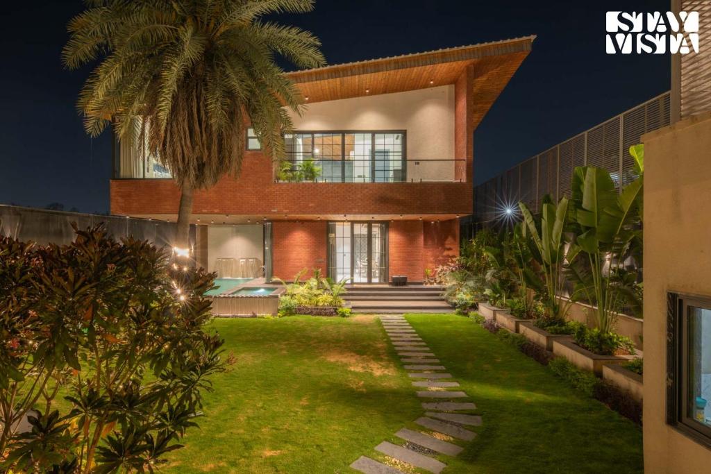 a house with a lawn in front of it at StayVista at Palm Tree Breeze with Pool, BBQ, Bonfire in Jaipur