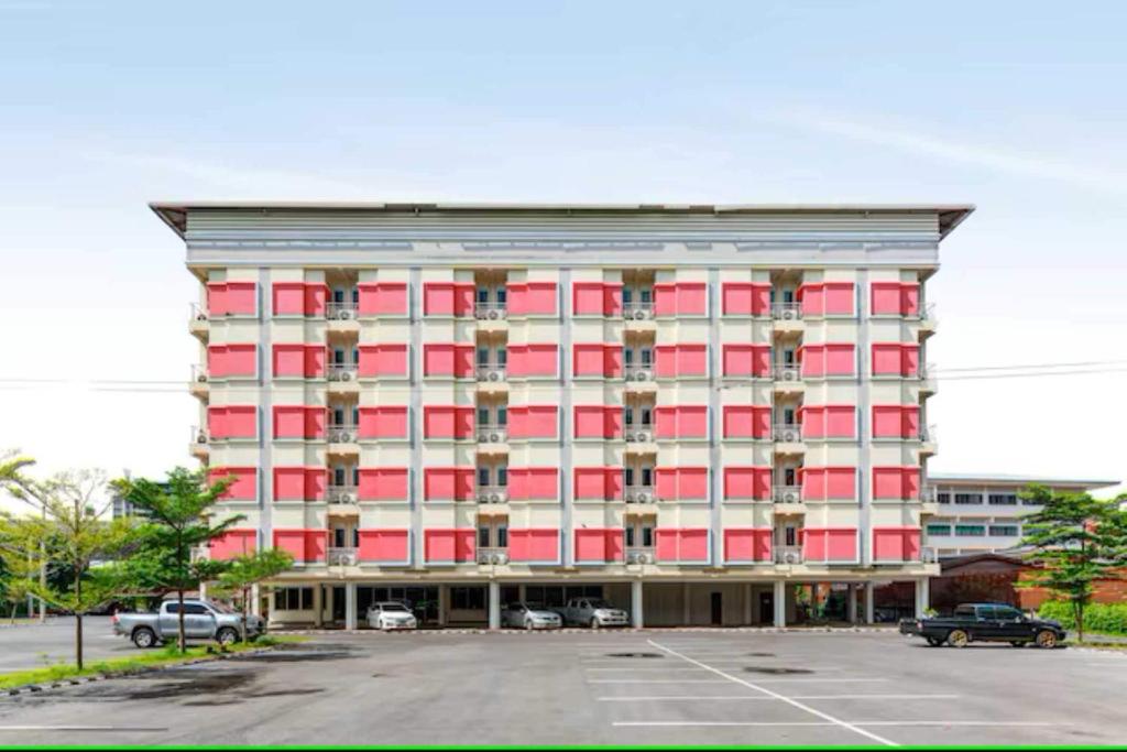 a large red building with cars parked in a parking lot at Dancenter VResotel in Bangkok