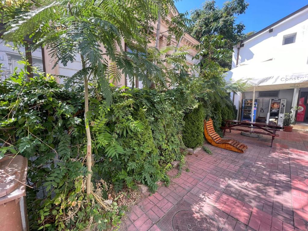 a building with a fence and a tree and a bench at Piata Uniri Cozy Inn in Bucharest