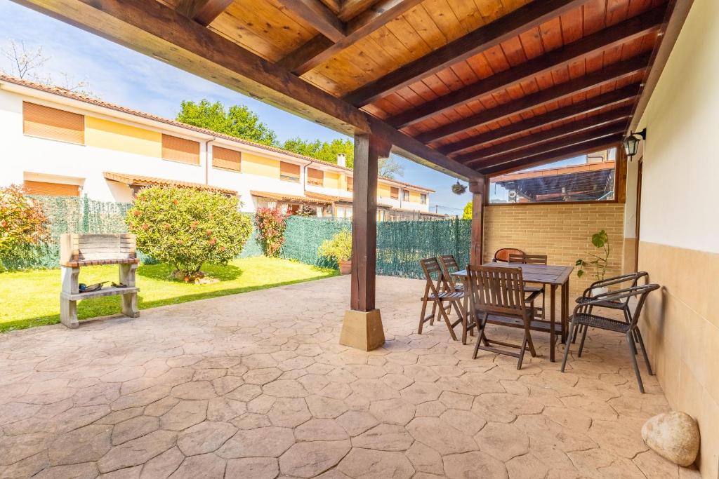 a patio with a table and chairs under a wooden pergola at La Pergola in Santillana del Mar