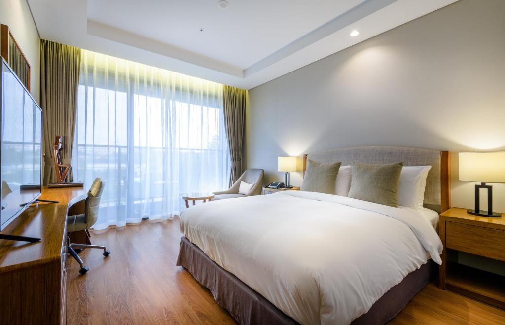 a hotel room with a large bed and a desk at Parksunshine Jeju in Seogwipo
