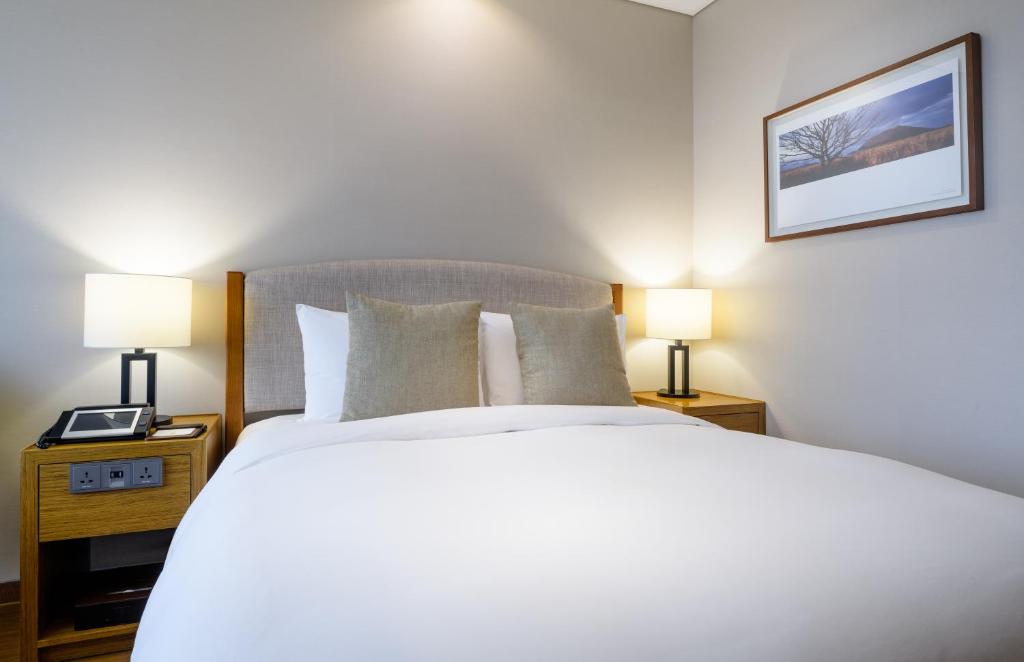 a bedroom with a large white bed with two lamps at Parksunshine Jeju in Seogwipo