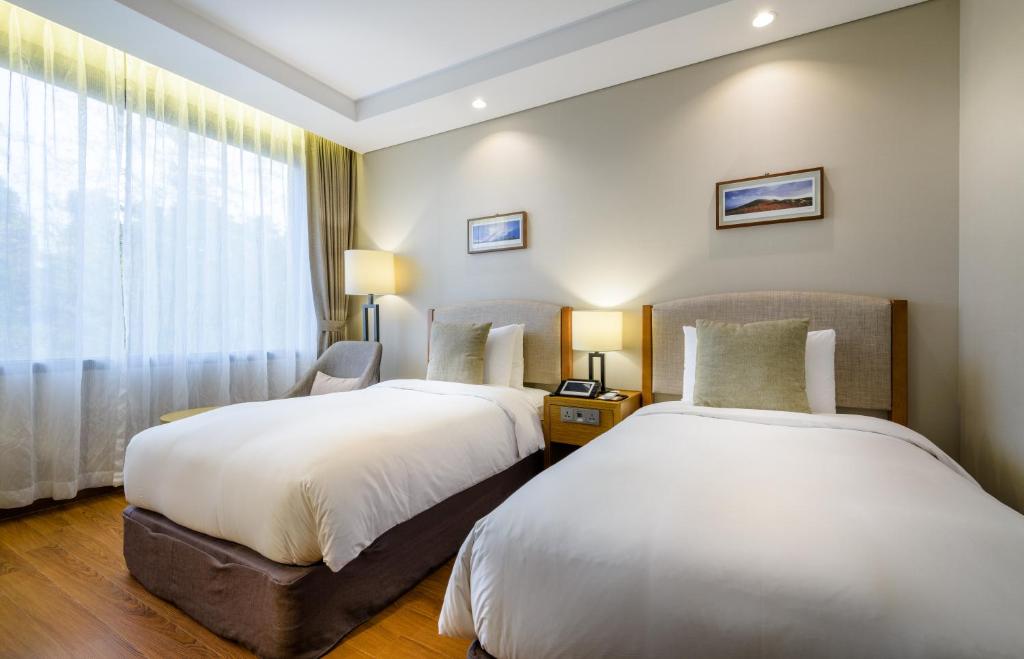 two beds in a hotel room with a window at Parksunshine Jeju in Seogwipo