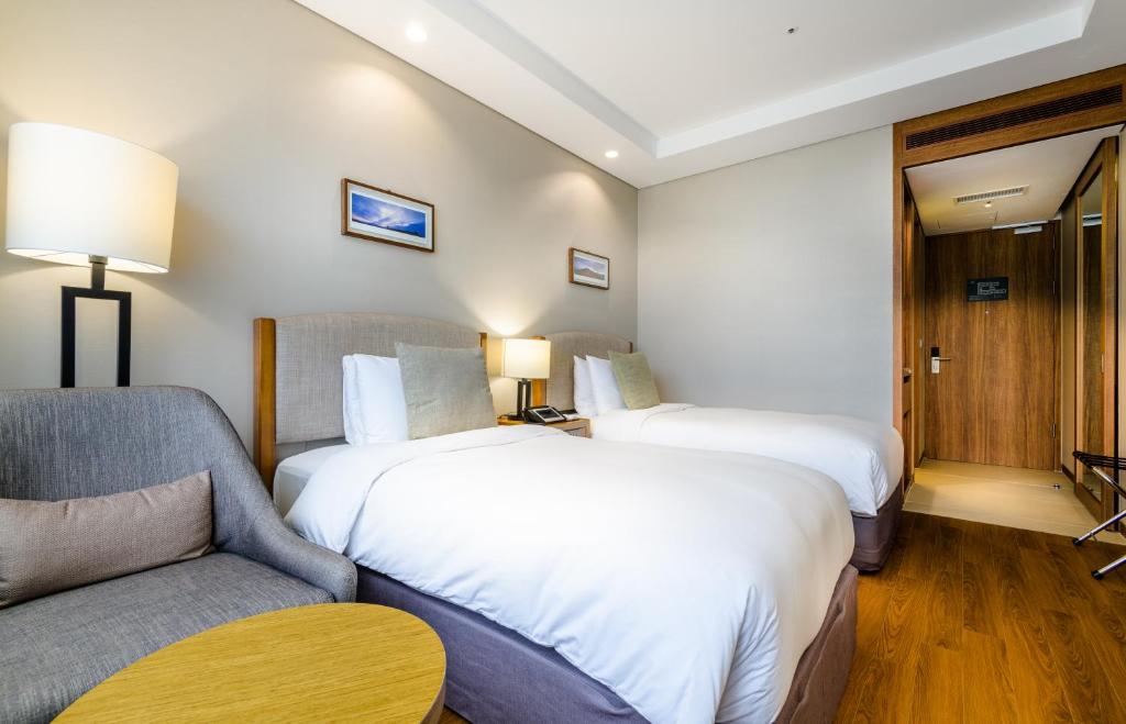 a hotel room with two beds and a couch at Parksunshine Jeju in Seogwipo