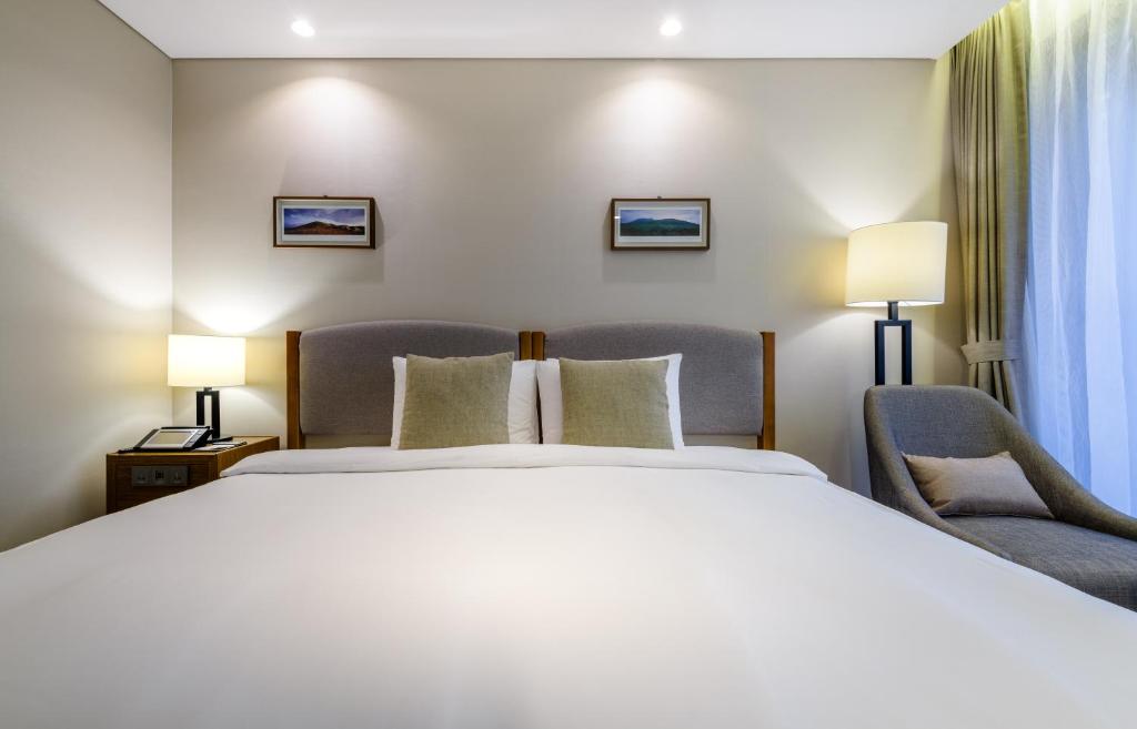 a hotel room with a bed and two chairs at Parksunshine Jeju in Seogwipo