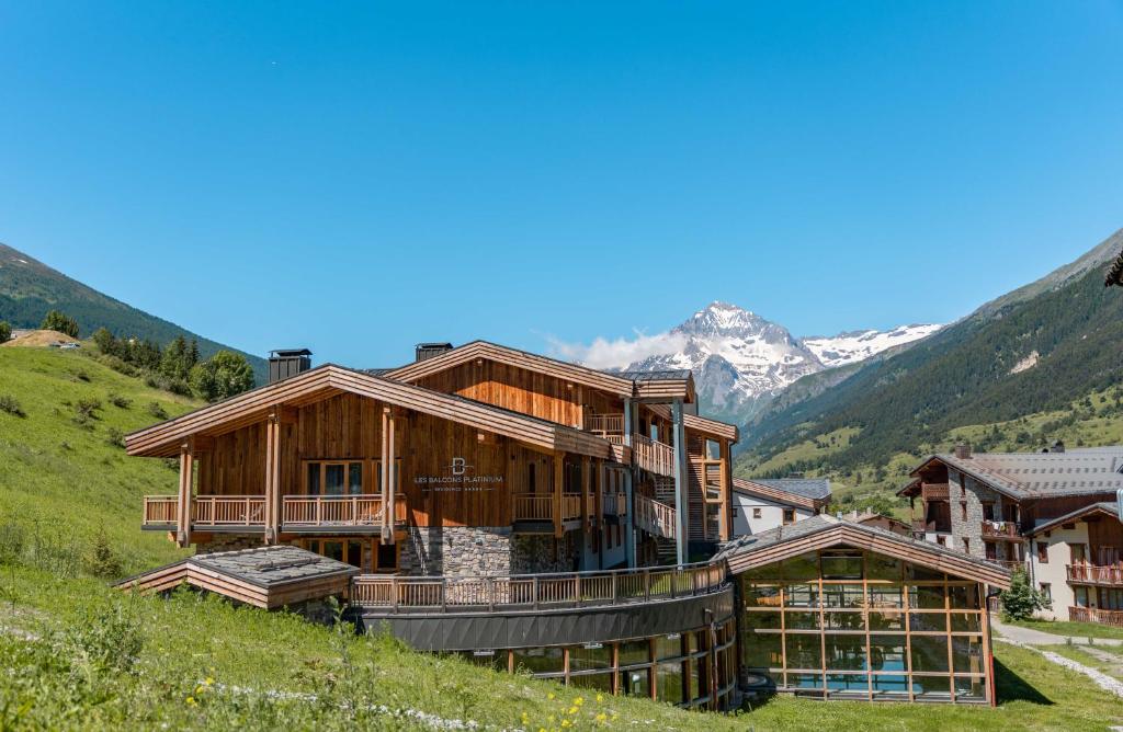 a house on a hill with mountains in the background at Les Balcons Platinium Val Cenis in Lanslevillard