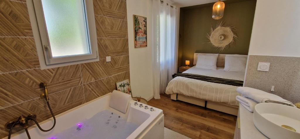 a bathroom with a bed and a tub and a sink at Green love & Spa - Villa Romantique in Saint-Laurent-de-Médoc