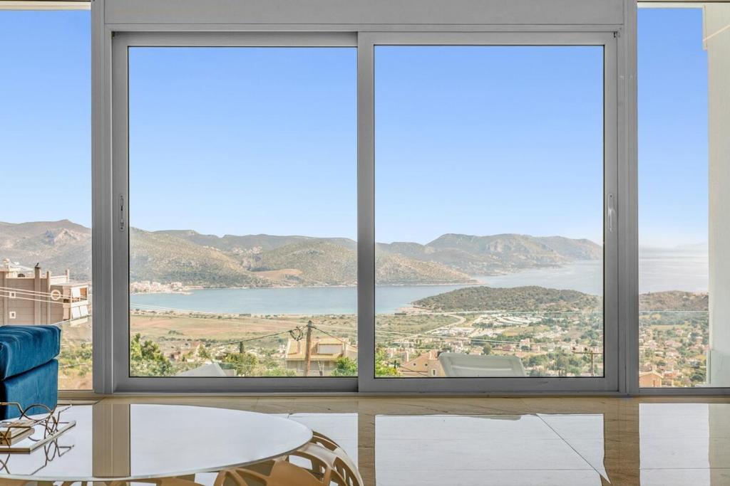 a room with three windows and a table and chairs at Sea Breeze Retreat with Private Pool in Saronida
