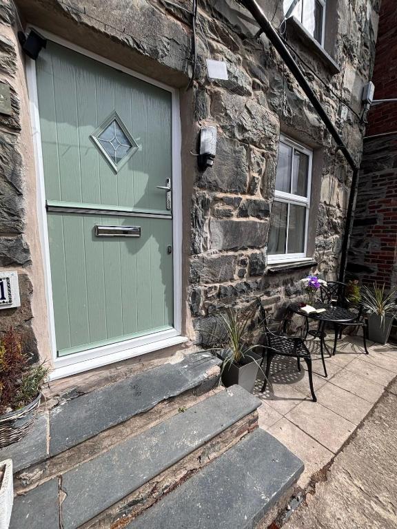 a green door on the side of a stone building at The Cottage on the Rock in Barmouth
