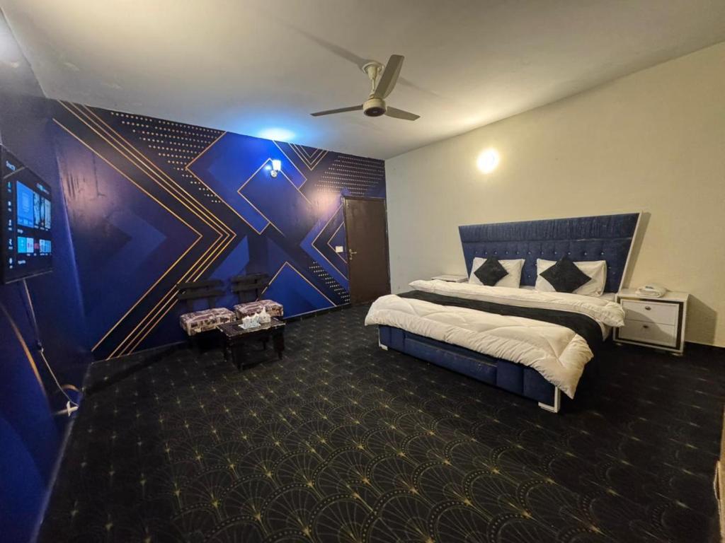 a bedroom with a large bed with a blue wall at Hotel Hayat Palace Johar Town in Lahore