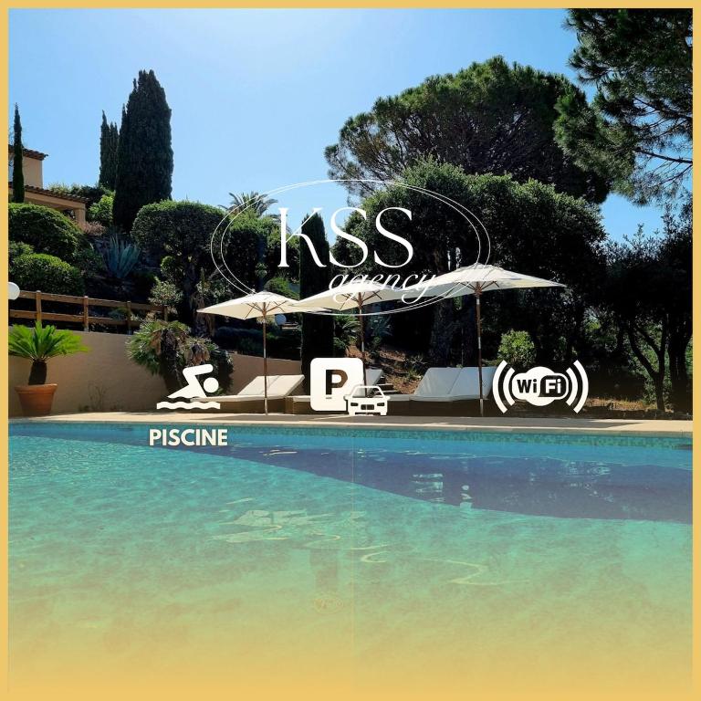 une piscine avec un parasol et des chaises à côté d'un complexe hôtelier dans l'établissement Villa 4 étoiles - parking - wifi - clim - piscine, à Sainte-Maxime