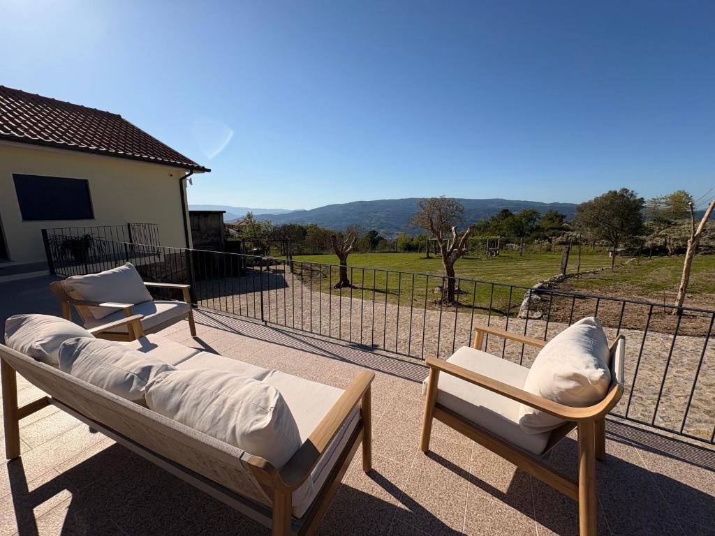 deux lits et des chaises sur un patio avec une clôture dans l'établissement Quinta de Fonte Coberta, à Ponte da Barca
