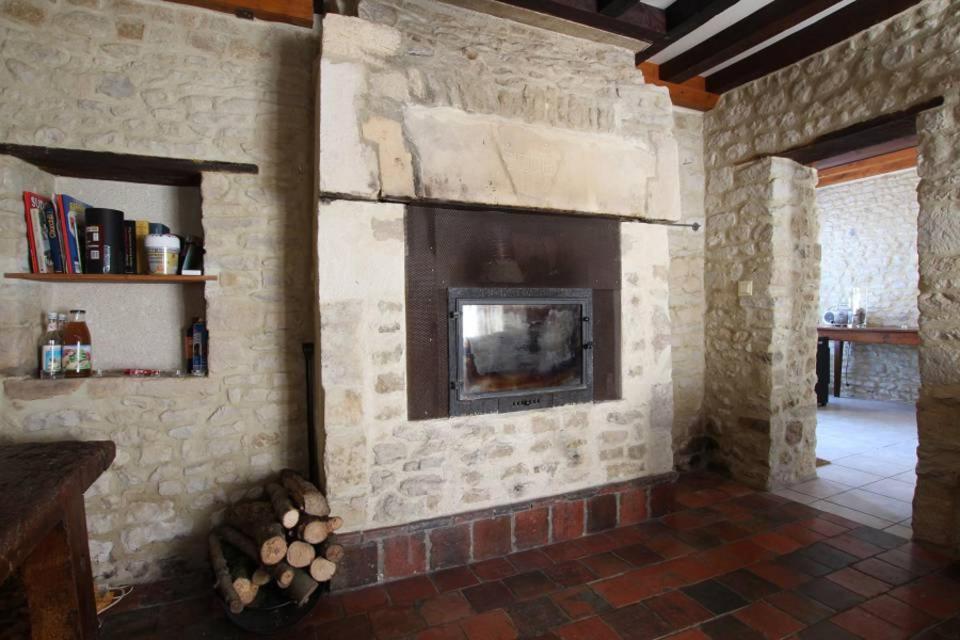 - un salon avec une cheminée en pierre dans une maison dans l'établissement Le Verger, à Étreham