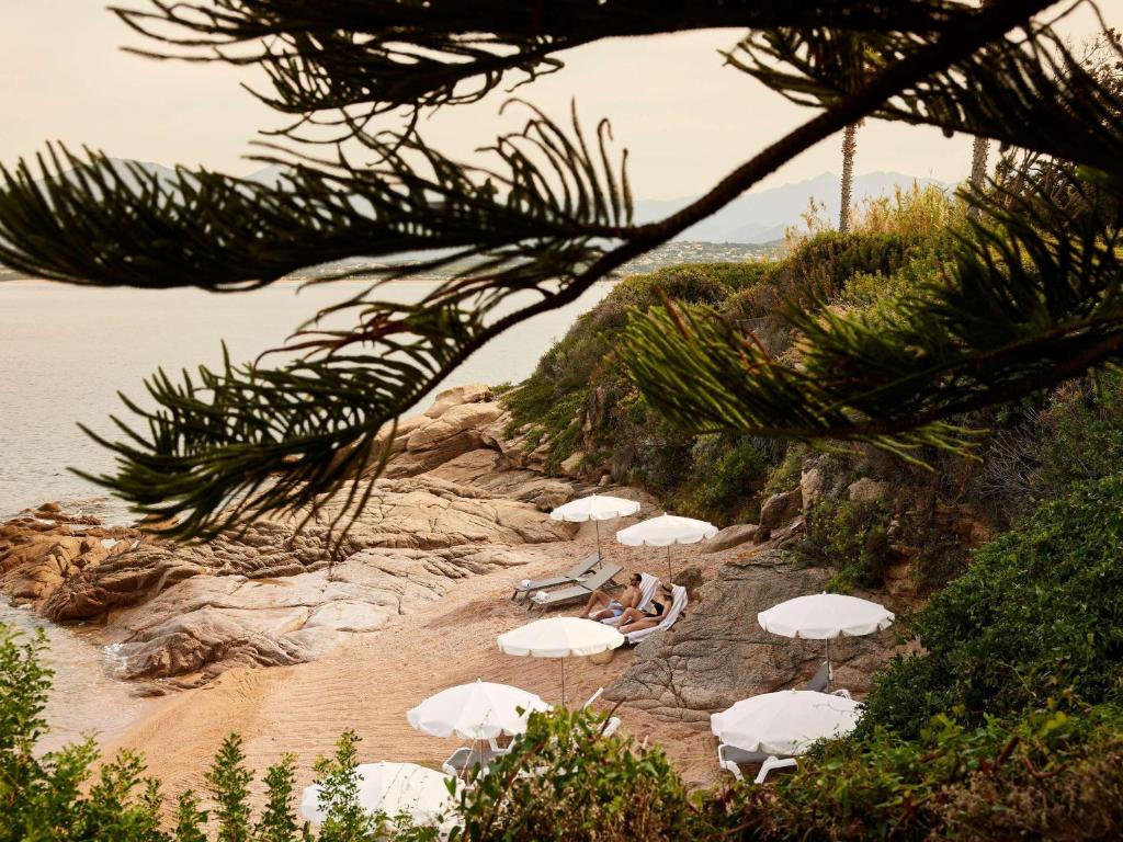 a group of white umbrellas on a beach at Sofitel Golfe d'Ajaccio Thalassa Sea & Spa in Ajaccio
