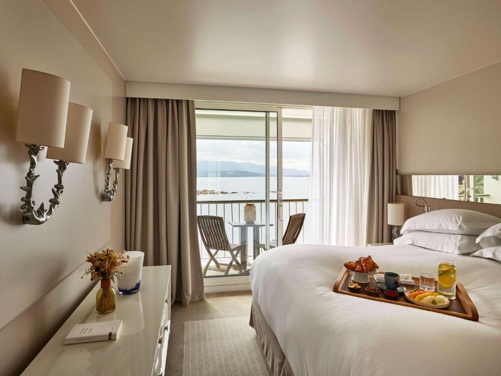 a hotel room with a bed with a tray of food on it at Sofitel Golfe d'Ajaccio Thalassa Sea & Spa in Ajaccio