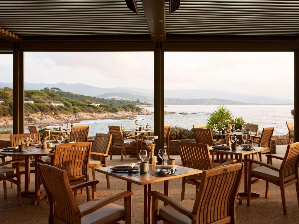 a restaurant with tables and chairs and a view of the water at Sofitel Golfe d'Ajaccio Thalassa Sea & Spa in Ajaccio