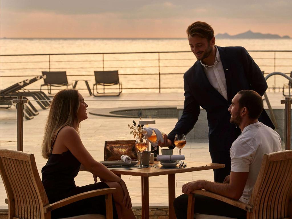 a group of three people sitting at a table with wine glasses at Sofitel Golfe d'Ajaccio Thalassa Sea & Spa in Ajaccio