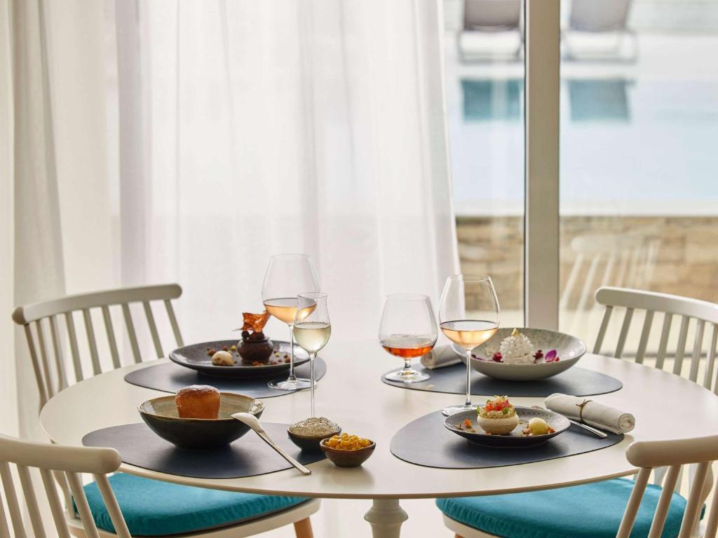 a table with plates of food and wine glasses at Sofitel Golfe d'Ajaccio Thalassa Sea & Spa in Ajaccio