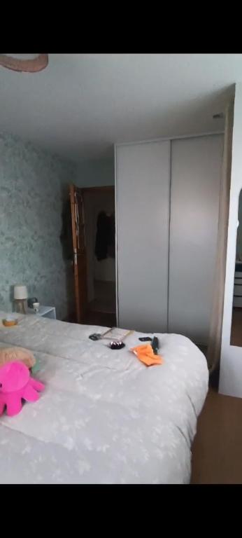 une chambre avec un lit blanc avec des objets roses dessus dans l'établissement Pivoinie, à Fleury-les-Aubrais