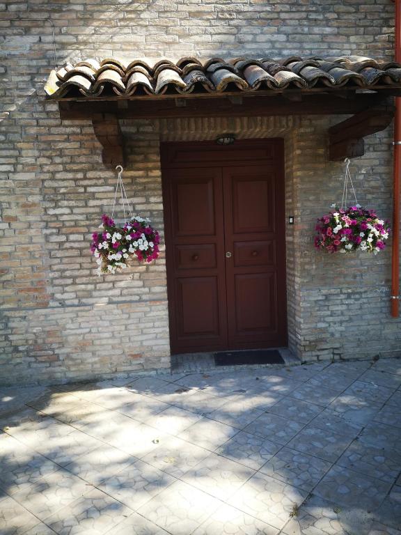 a brick building with a brown door and flowers at Holiday Inn Mirida in Pesaro
