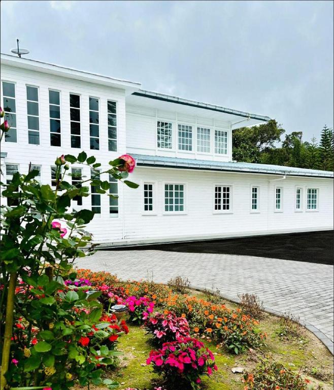 a white building with flowers in front of it at Riverview Bungalow in Cameron Highlands in Tanah Rata