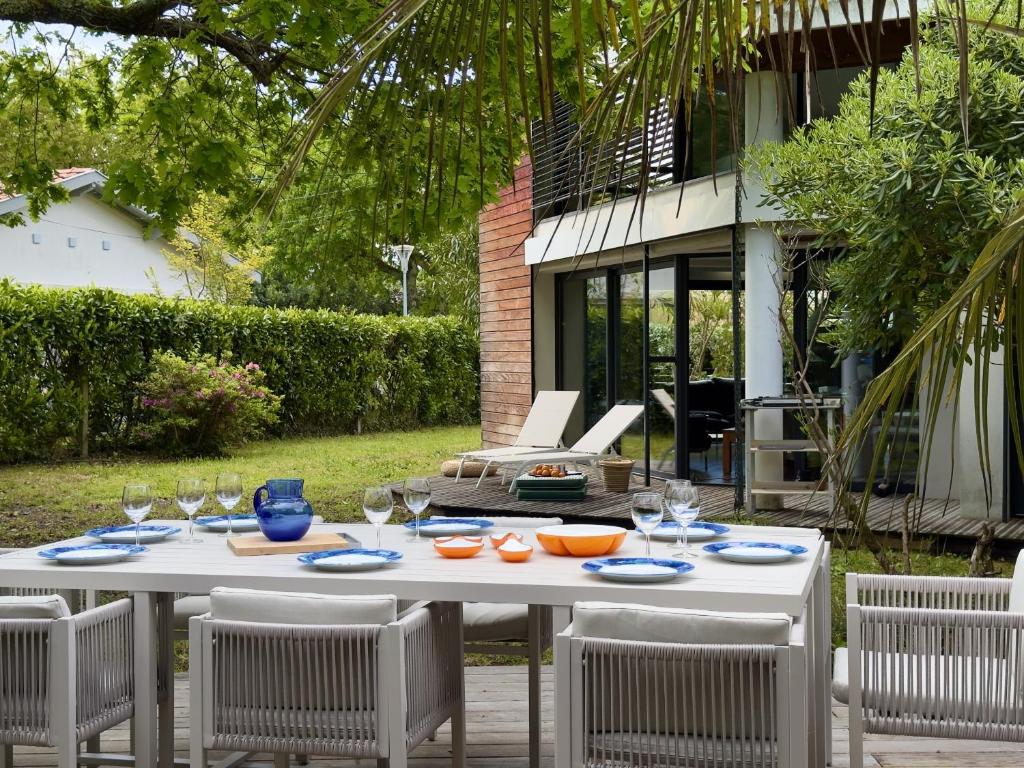 - une table blanche avec des chaises et des verres à vin dans l'établissement 950m plage - Maison architecte 4 adultes - 2enfants, à Andernos-les-Bains