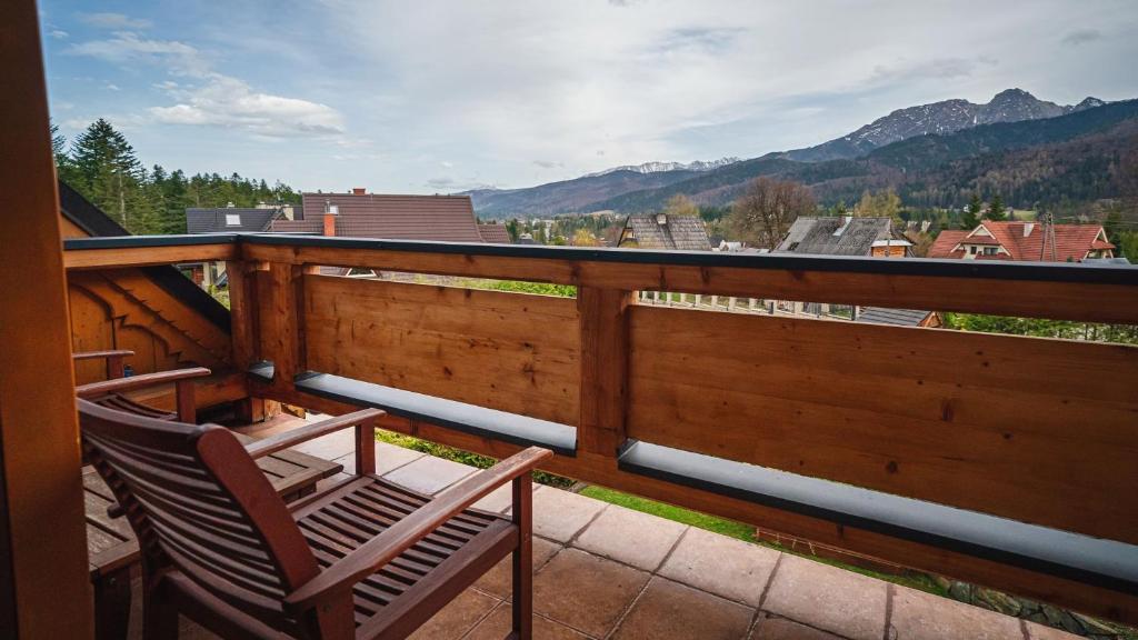 two chairs sitting on a balcony with a view of mountains at Sywarne, Sun & Snow in Kościelisko