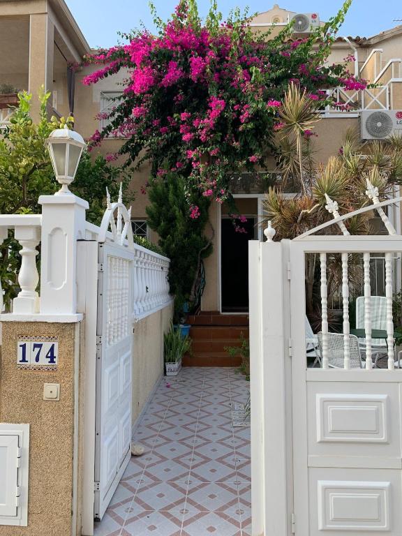 a house with a white fence and pink flowers at Charming duplex with pool in Torrevieja