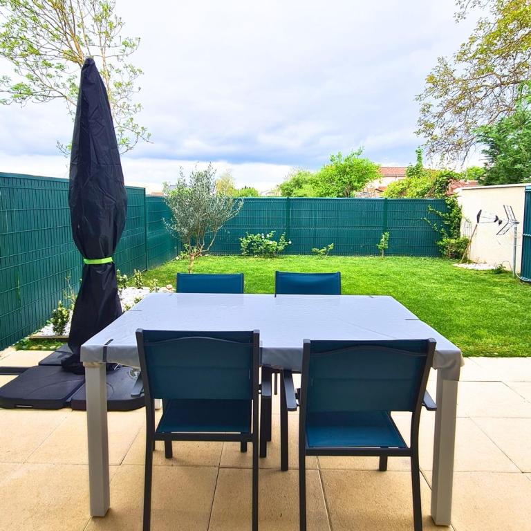 une table blanche avec quatre chaises bleues dans une cour dans l'établissement L'Escapade Enchantée, à Leyment