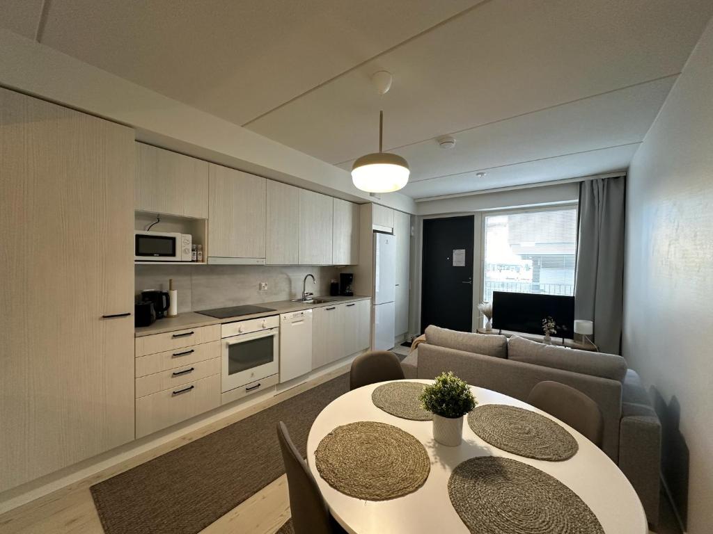 a kitchen and living room with two tables and a couch at Pramea Apartments Aallonharja 5 in Jyväskylä