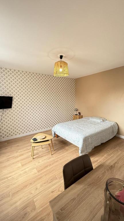 a bedroom with a bed and a table and a chair at Madeleine - Studio Charmant in Orléans