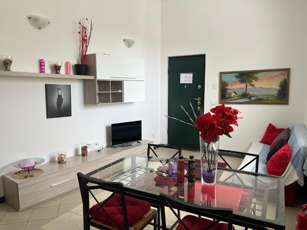a living room with a glass table with red roses at appartamento genziane in Genova