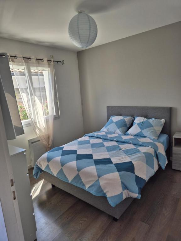 - une chambre avec un lit bleu et blanc et une fenêtre dans l'établissement La Gujannaise, à Gujan-Mestras
