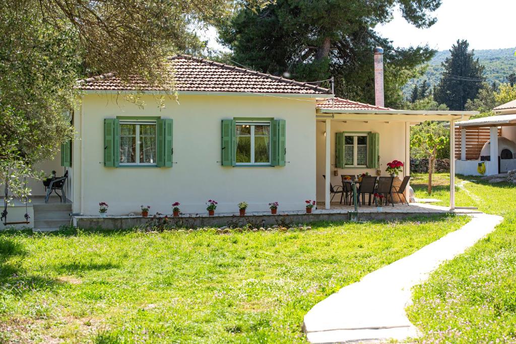 a small house with green windows and a yard at Eleonas Country House in Marantochori