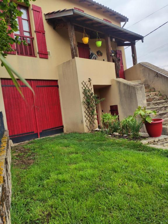 une maison avec des portes rouges et une cour verdoyante dans l'établissement Maison de campagne chaleureuse, à Léotoing