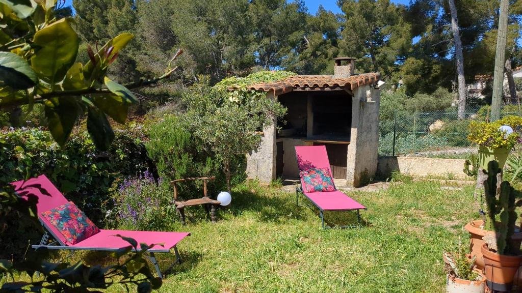 Deux chaises roses assises dans l'herbe dans une cour dans l'établissement MAISONNETTE KALIS CALME avec CLIMATISATION PARKING JARDIN CADRE CAMPAGNE plages à pieds, à Bandol