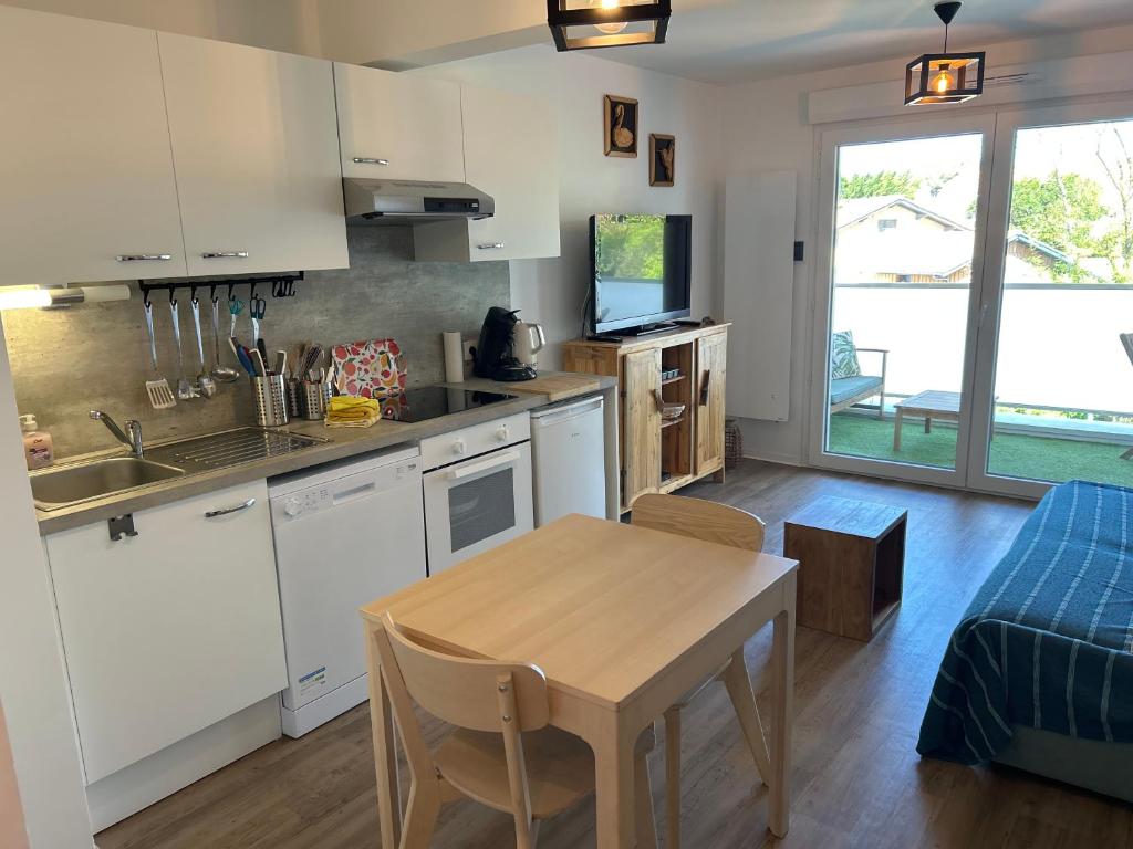 une cuisine avec des placards blancs et une table avec une table dans l'établissement Au cœur de Lacanau Océan Appartement neuf avec parking, à Lacanau-Océan