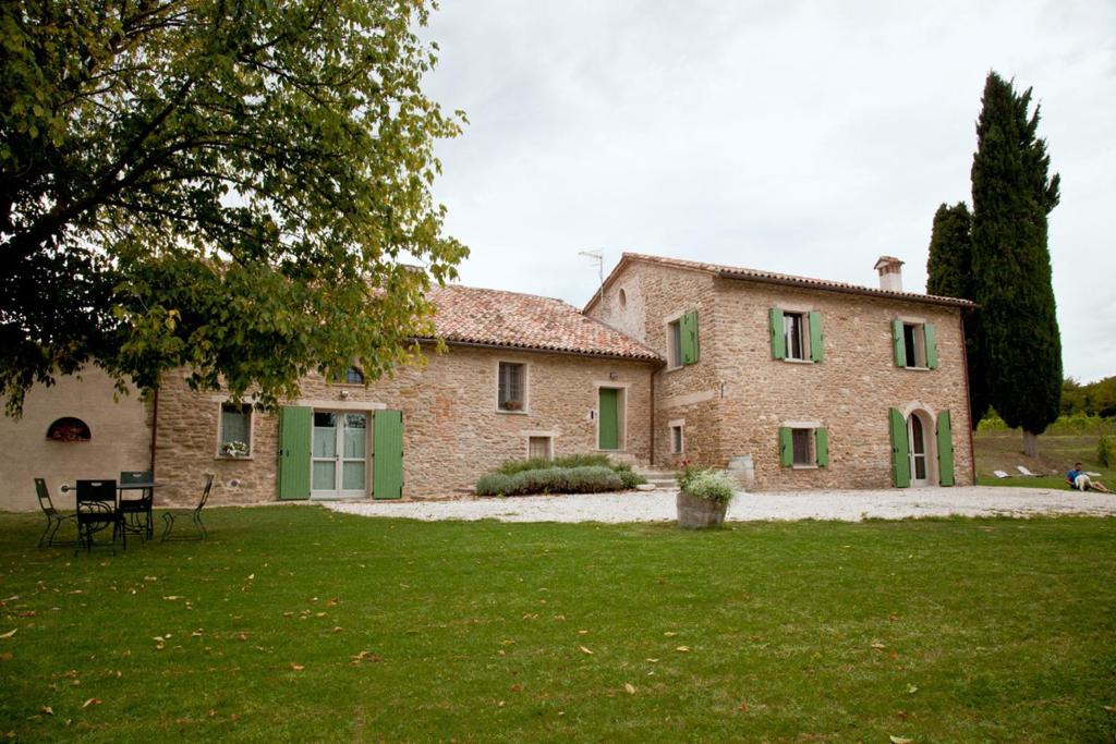 une grande maison en pierre avec des portes vertes et une cour dans l'établissement Azienda Agricola Baccagnano, à Brisighella