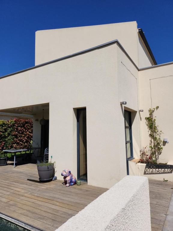 un ours en peluche assis sur une terrasse devant une maison blanche dans l'établissement Annie-laure, à La Celle-sous-Gouzon