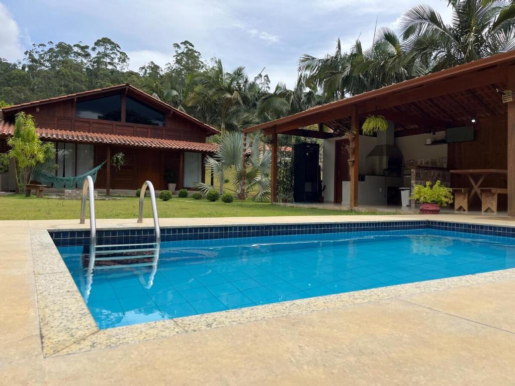 a villa with a swimming pool in front of a house at Chácara cantinho na roça, Domingos Martins - Espirito Santo in Domingos Martins