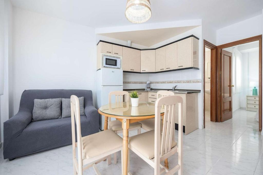 a kitchen and dining room with a table and a couch at APARTAMENTOS CARMEN in Maro