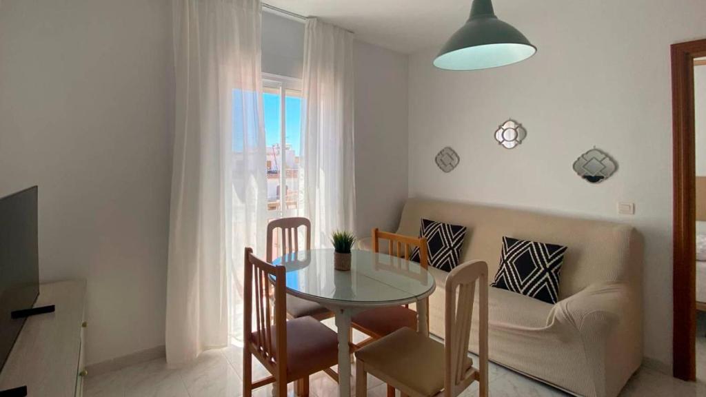 a dining room with a table and chairs and a couch at APARTAMENTOS CARMEN in Maro