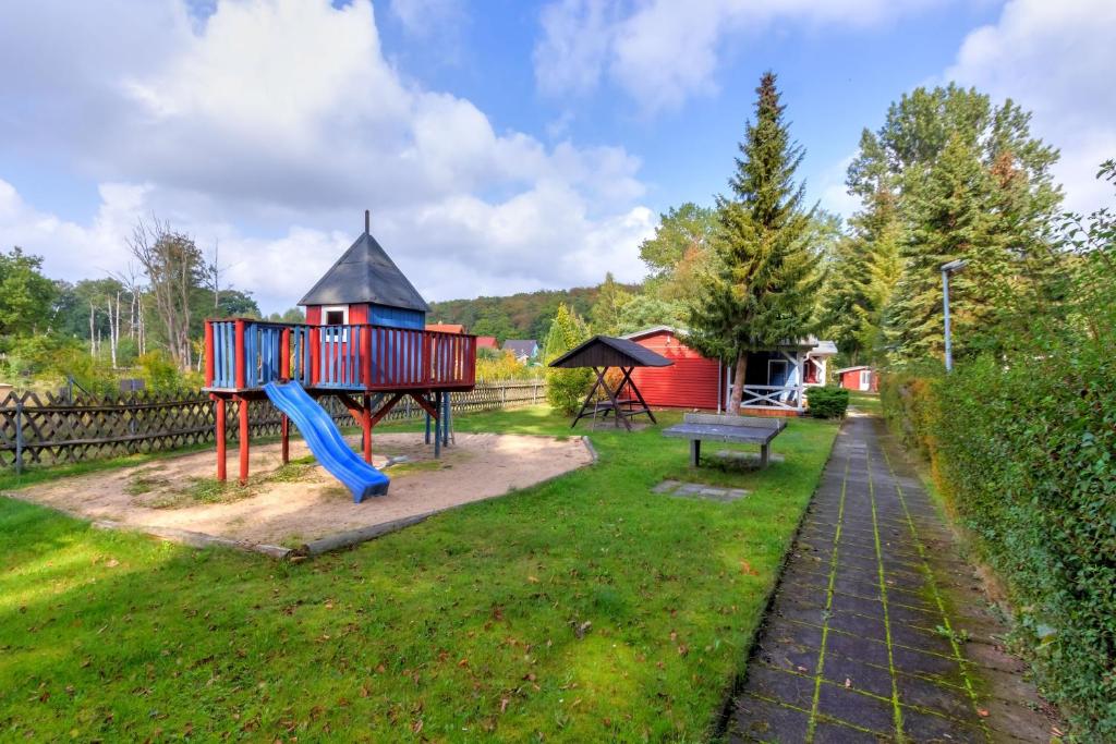a playground with a blue slide in a yard at Korswandt, Ostseebungalow in Korswandt