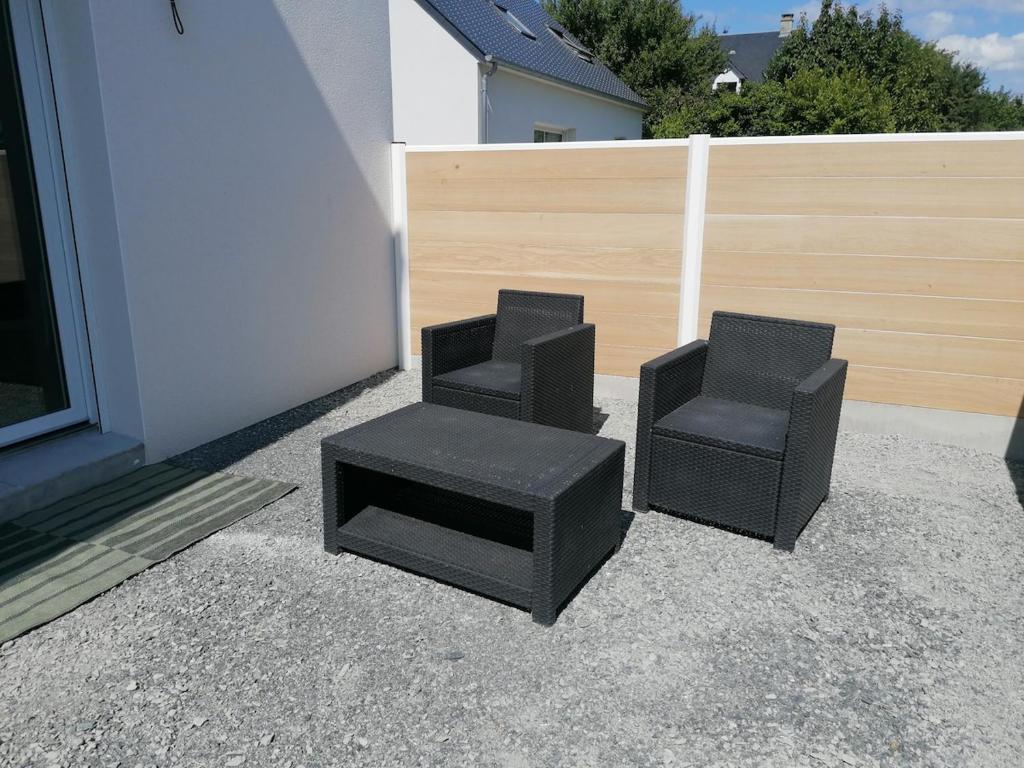 two black chairs and a stool next to a building at Studio cosy in Granville