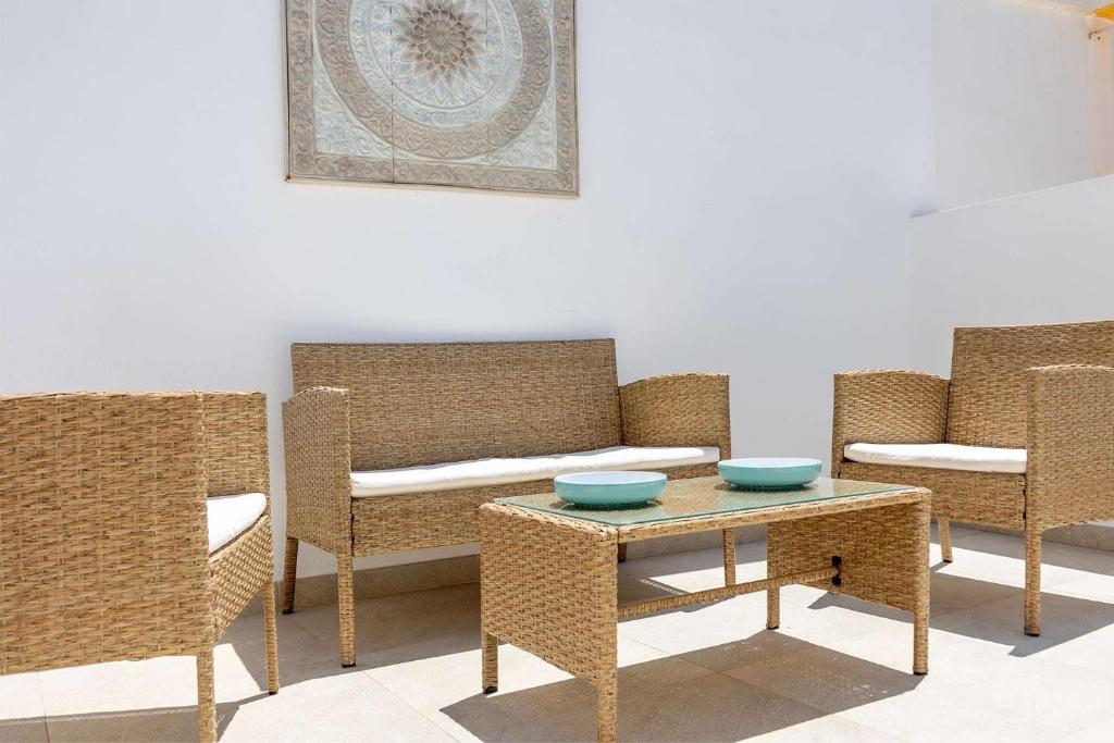a room with wicker chairs and a table with bowls on it at APARTAMENTOS CARMEN in Maro