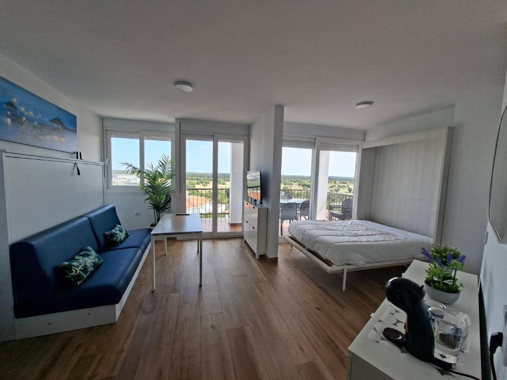 a living room with a blue couch and a bed at Apartamento con piscina in Matalascañas