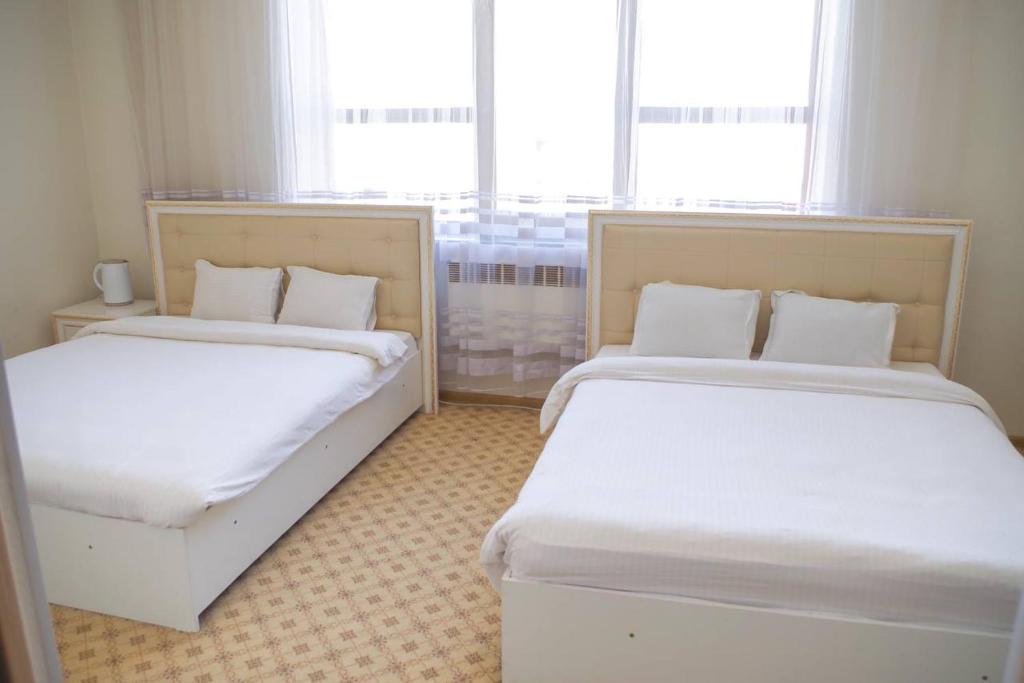 two beds in a small room with two windows at Sultan Jalal-Abad in Jalal-Abad